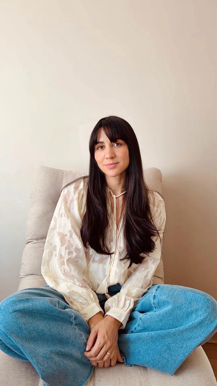 Amanda Lima, psicóloga, sentada em uma poltrona clara, com expressão serena