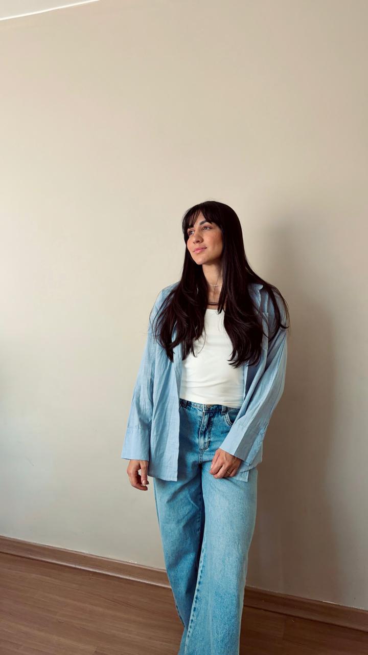 Amanda Lima em pé, de camisa azul-clara, olhando para o lado